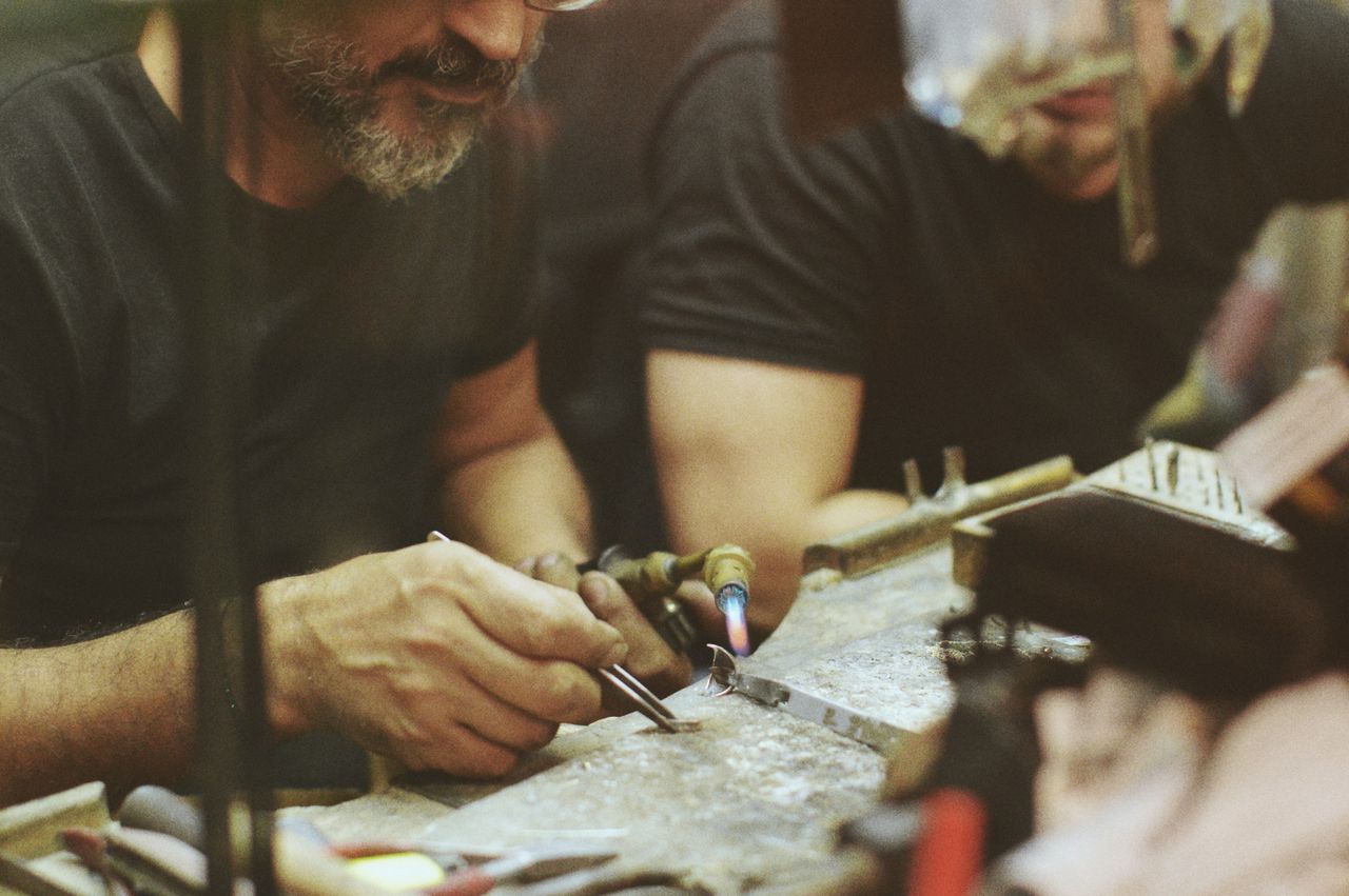 Close-up of artisans focusing on precision metalwork with welding tools in a workshop.
