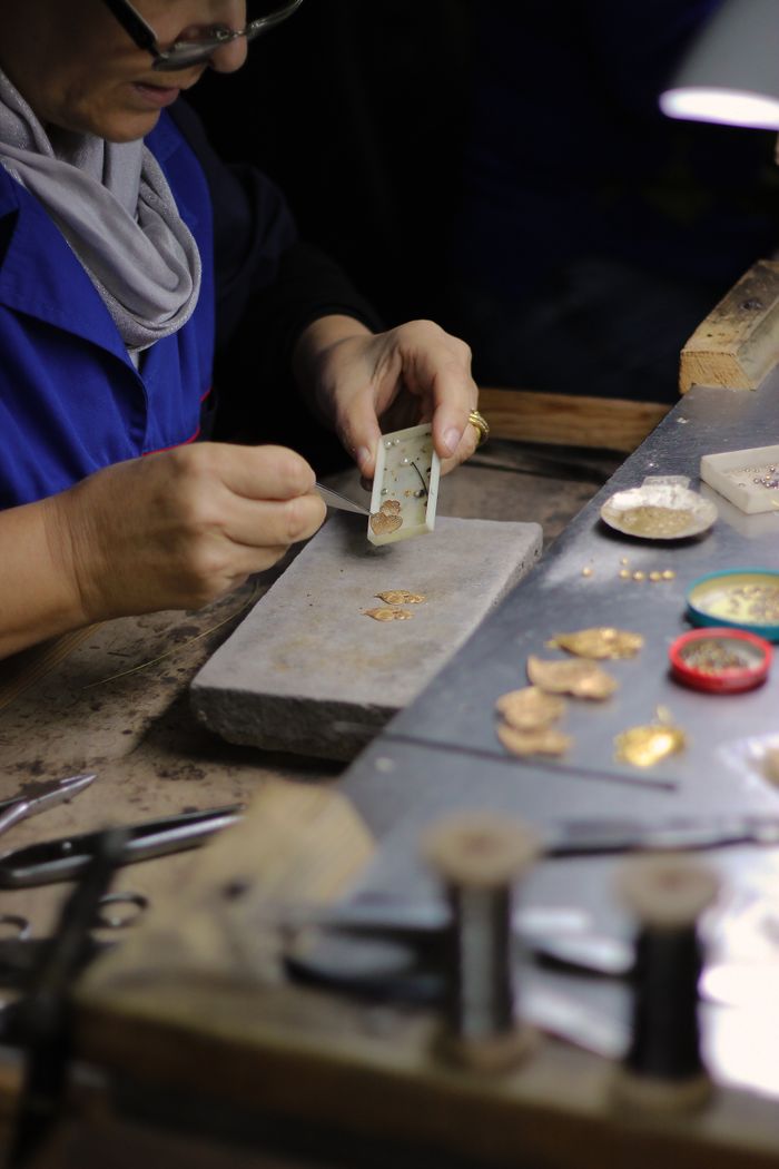 Hands of an artisan delicately crafting gold jewelry in a traditional Portuguese workshop.