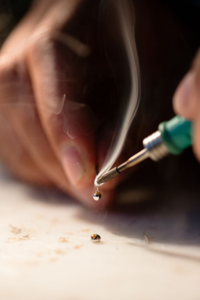 Detailed shot of soldering with smoke and precision handwork.